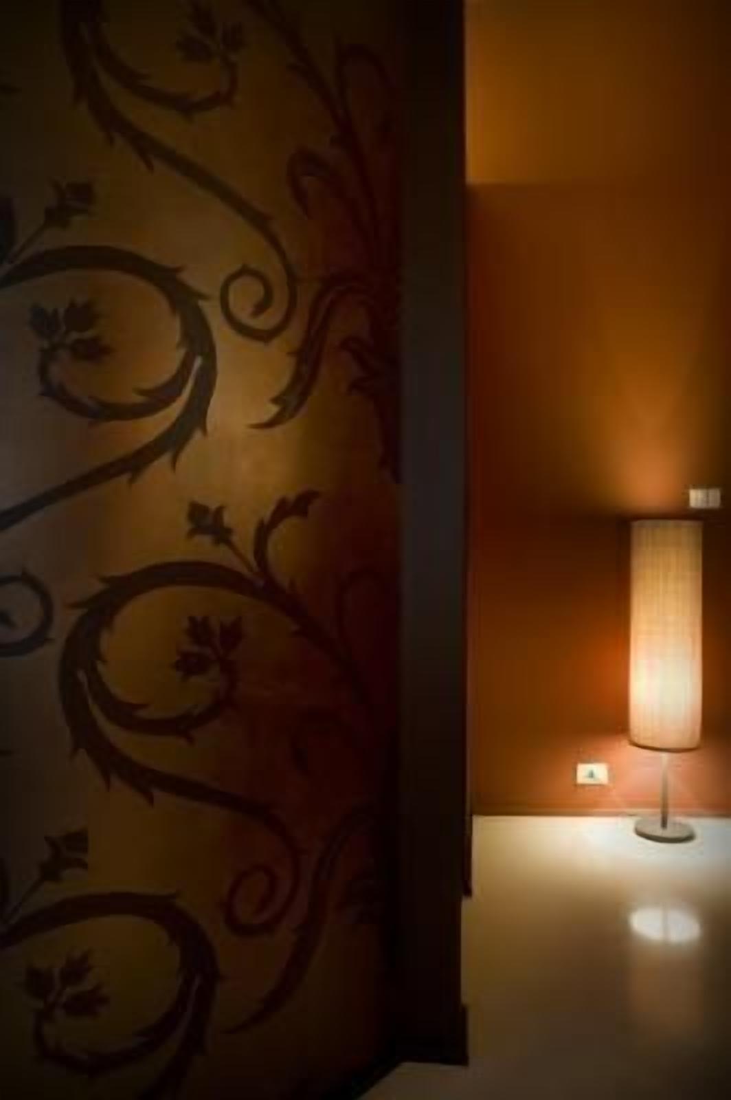 Pared con motivos florales y una lámpara en una habitación con poca luz.