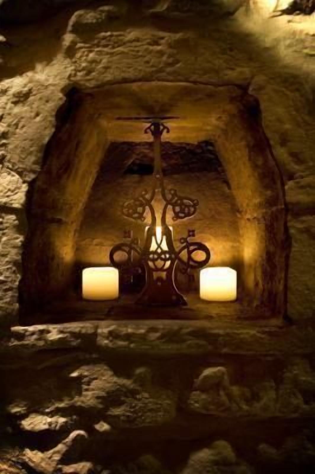 Una chimenea de piedra con una rejilla metálica decorativa y dos velas.