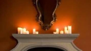 A fireplace with a white mantel, lit candles, and two decorative figures.
