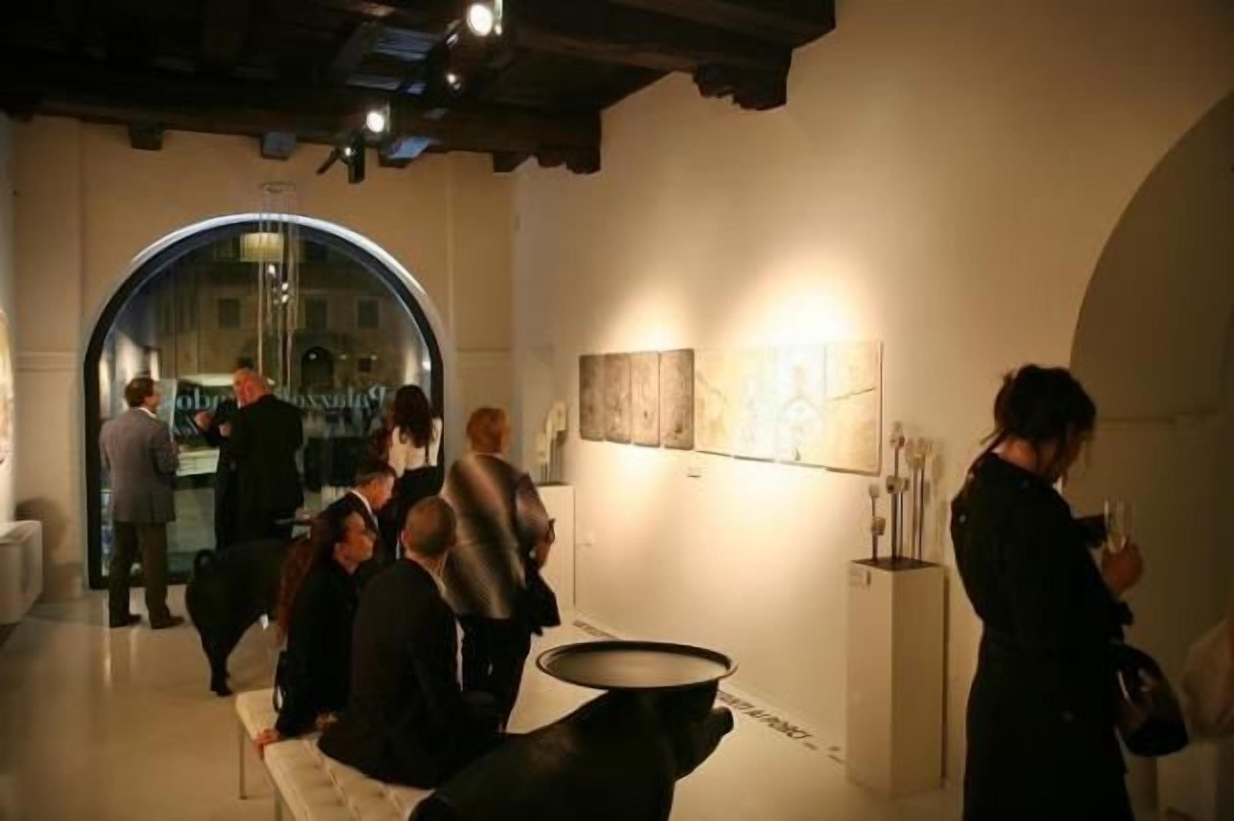 An indoor art gallery with a circular skylight, a reception area, and a wall with framed artwork.