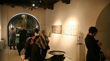 An indoor art gallery with a circular skylight, a reception area, and a wall with framed artwork.