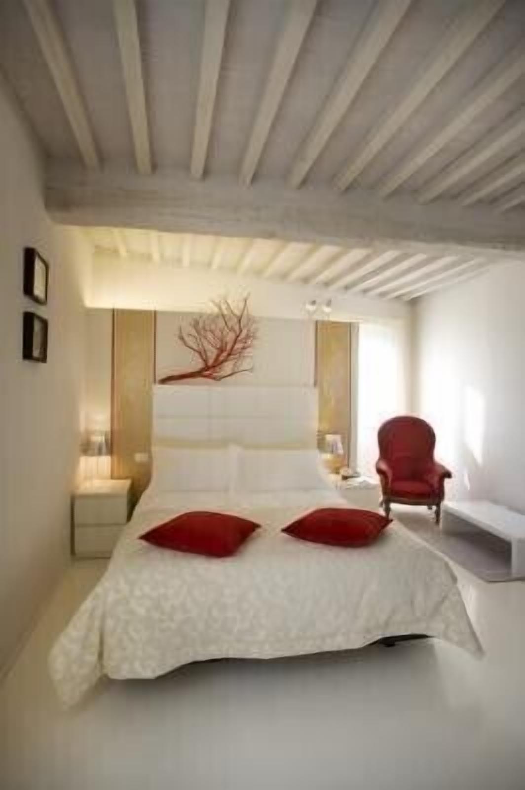 Un dormitorio moderno con una cama grande, una silla roja y un diseño minimalista.