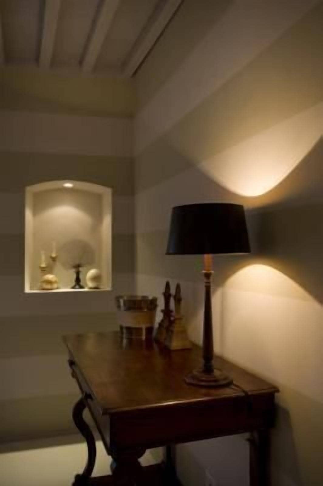 A dimly lit room with a wooden table, a lamp, and a small display case with decorative items.