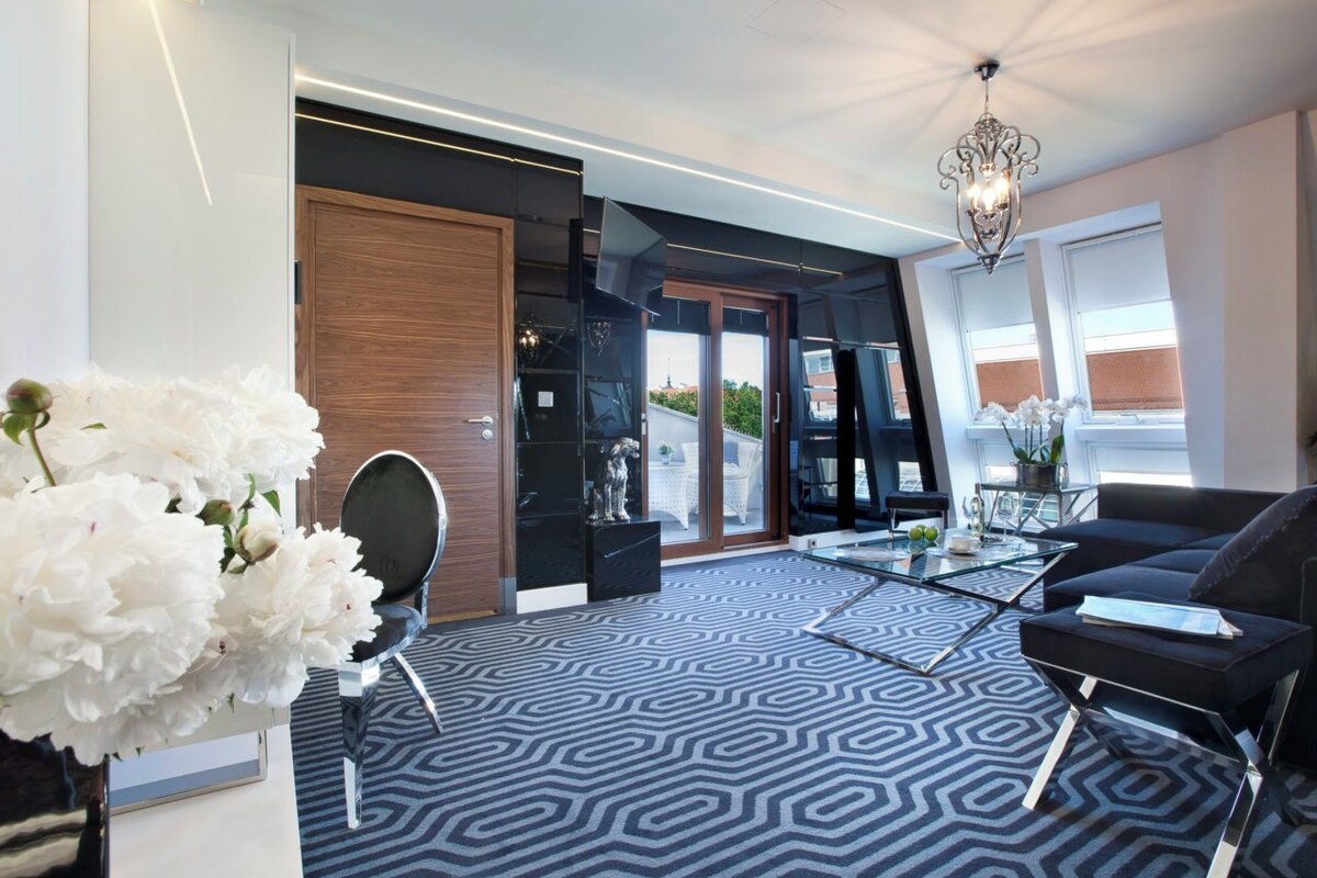 A modern living room with a patterned carpet, a sofa, a coffee table, and a decorative mirror.