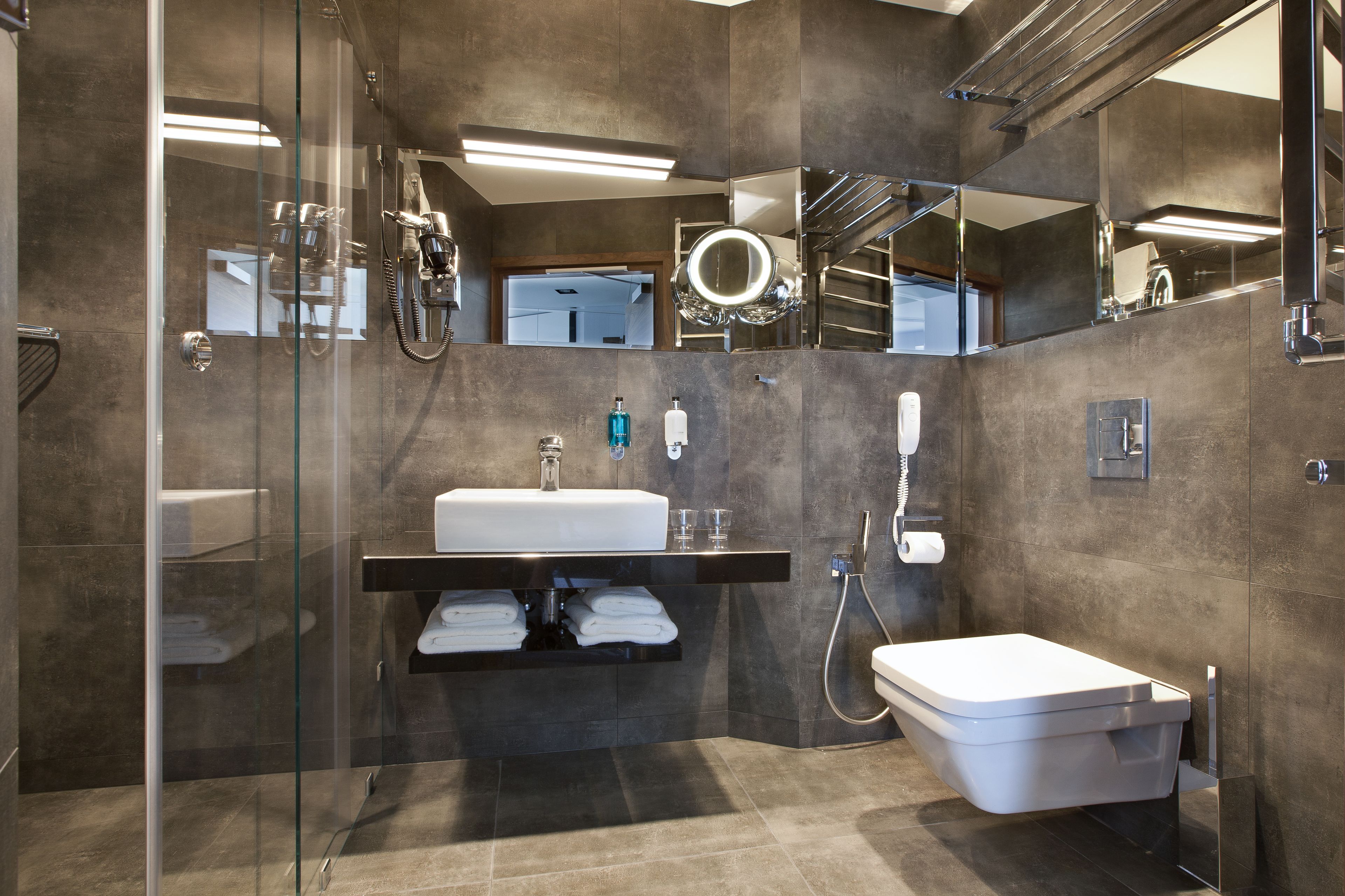 Een moderne badkamer met een douchecabine van glas, een wit wastafelmeubel en een toilet.