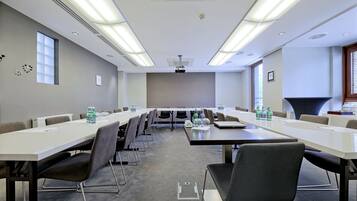 A conference room with long tables and chairs, equipped with water bottles and a projector.