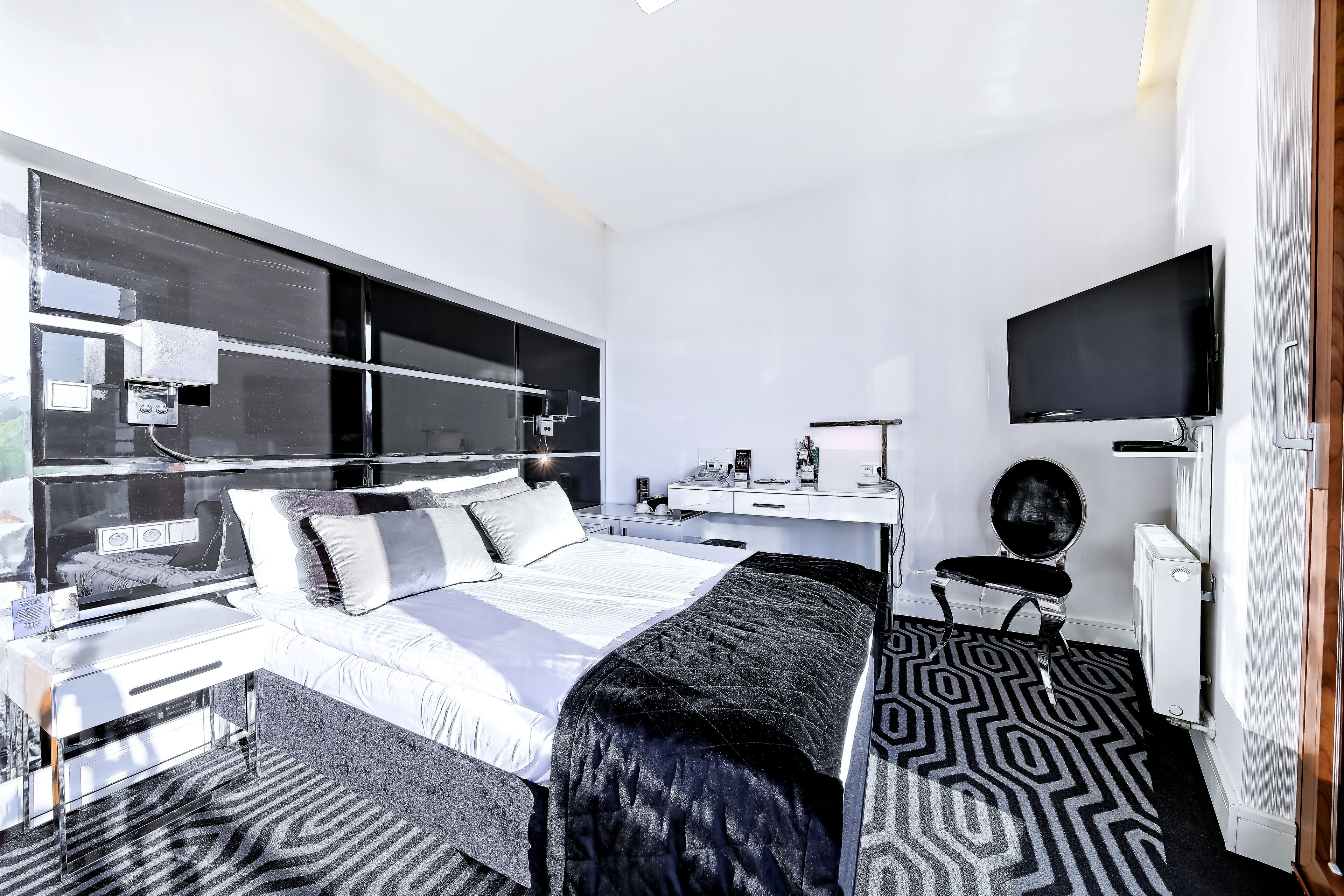 Una habitación de hotel moderna con una cama grande, un escritorio, un televisor de pantalla plana y un ventanal amplio.