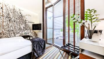 A modern bedroom with a bed, a map wall, a sliding glass door to a balcony, and a small plant on the nightstand.