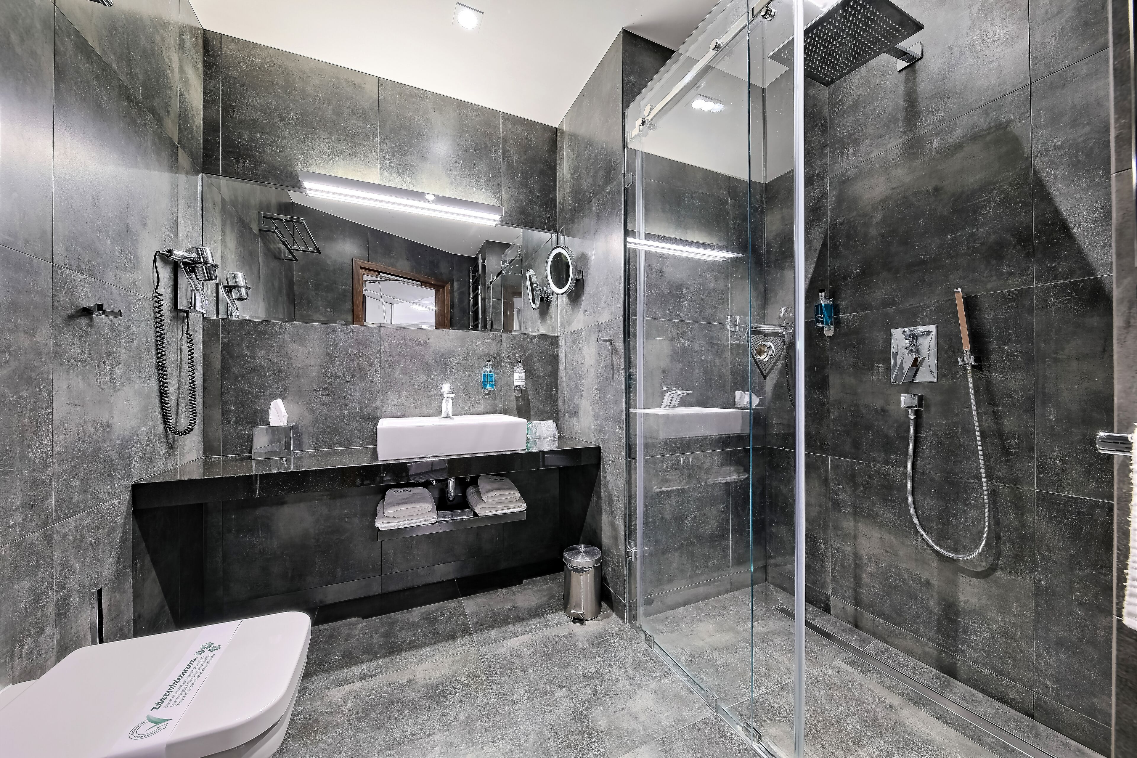 A modern bathroom with a glass-enclosed shower, a white sink, and a black vanity.