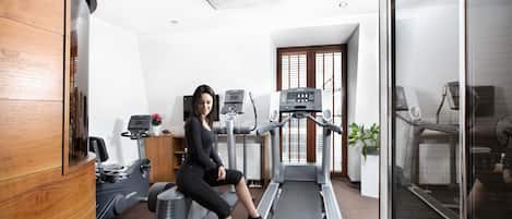 Un gimnasio con equipo de ejercicio, una cinta de correr y un espejo grande.