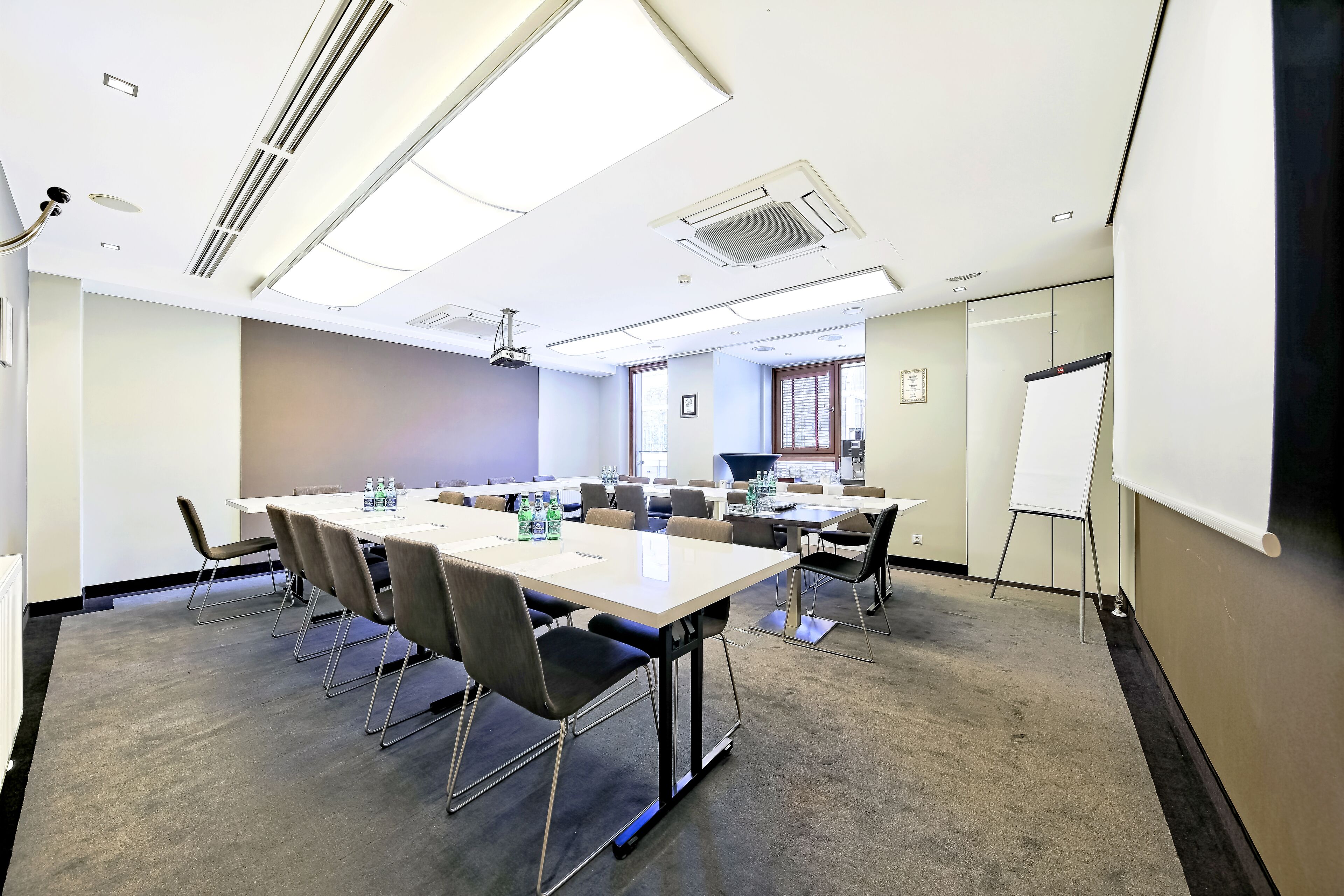 A conference room with a large table, chairs, a projector, and a whiteboard.