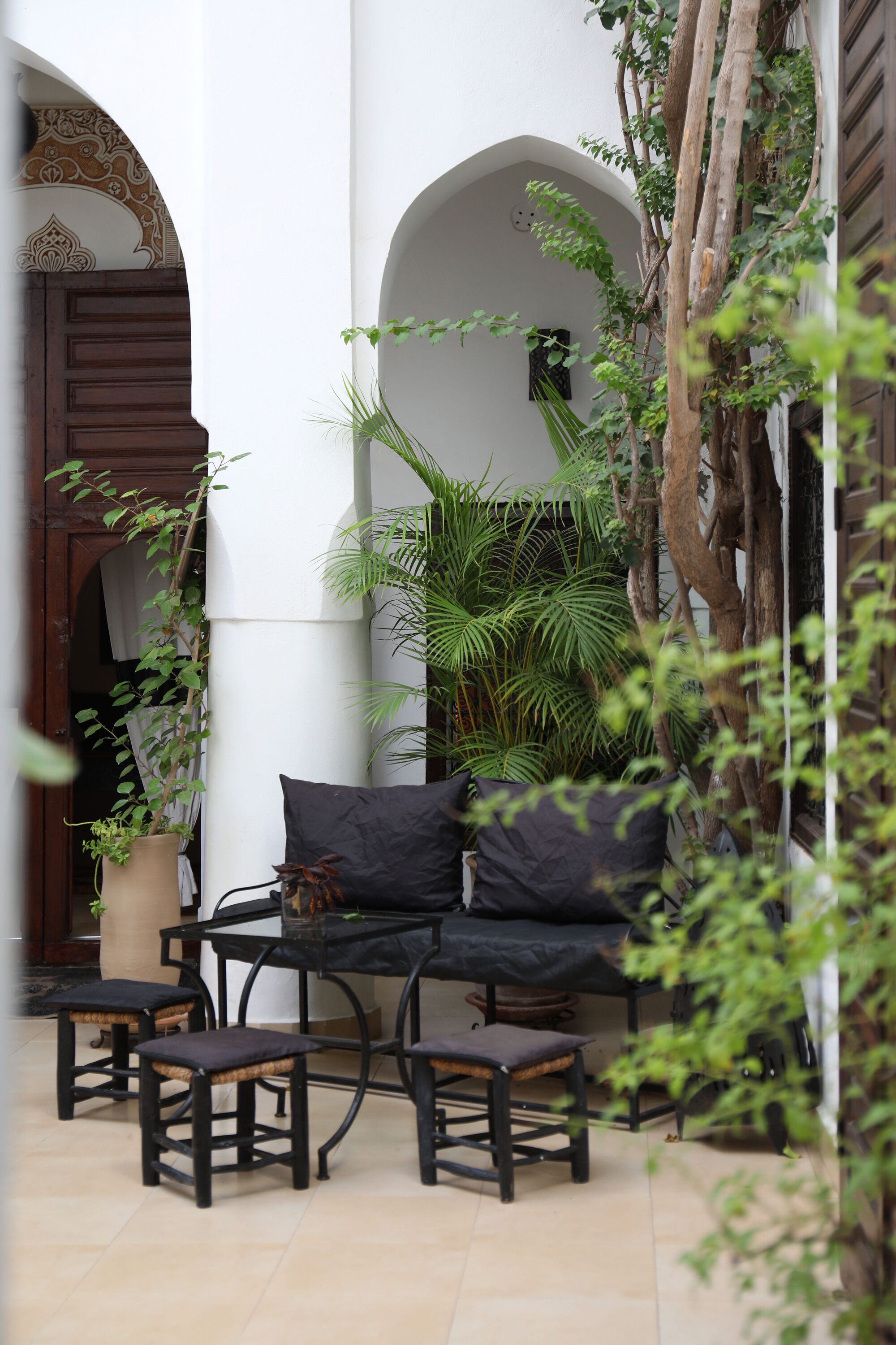 A courtyard with a black outdoor seating area, a potted plant, and a wooden door.