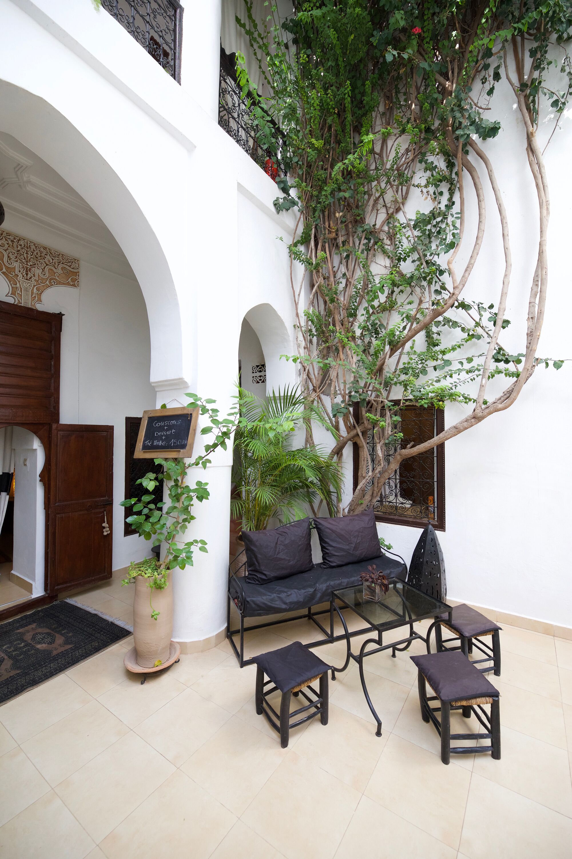 A courtyard with a seating area, a potted plant, and a signboard.