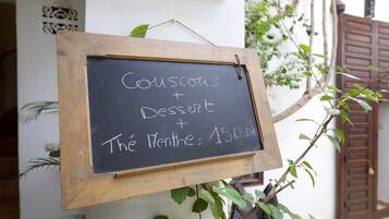 A chalkboard sign with the text "Couscous Dessert The Menthe: 150ml" mounted on a wooden frame.