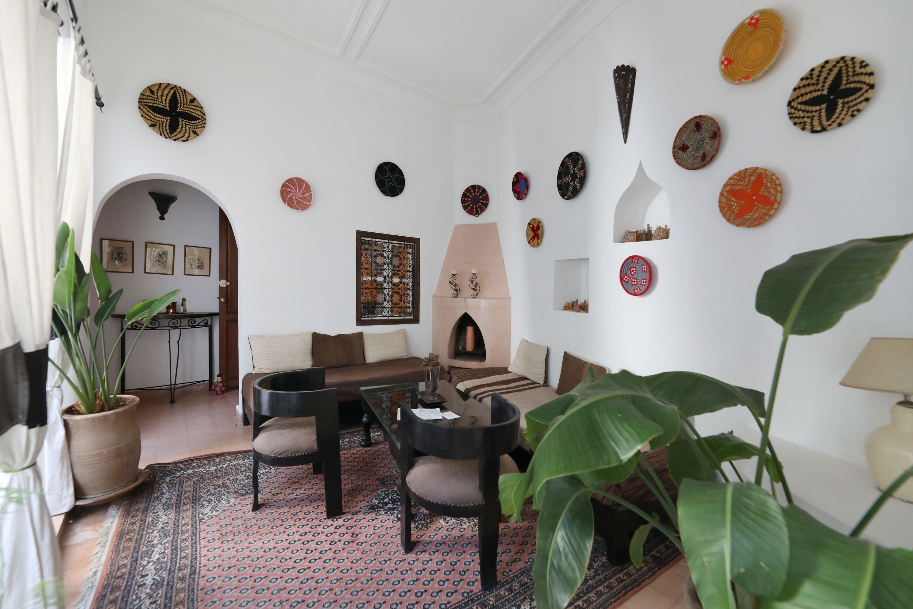 Un salon comprenant un canapé, des fauteuils, une table basse, une cheminée et une grande plante.