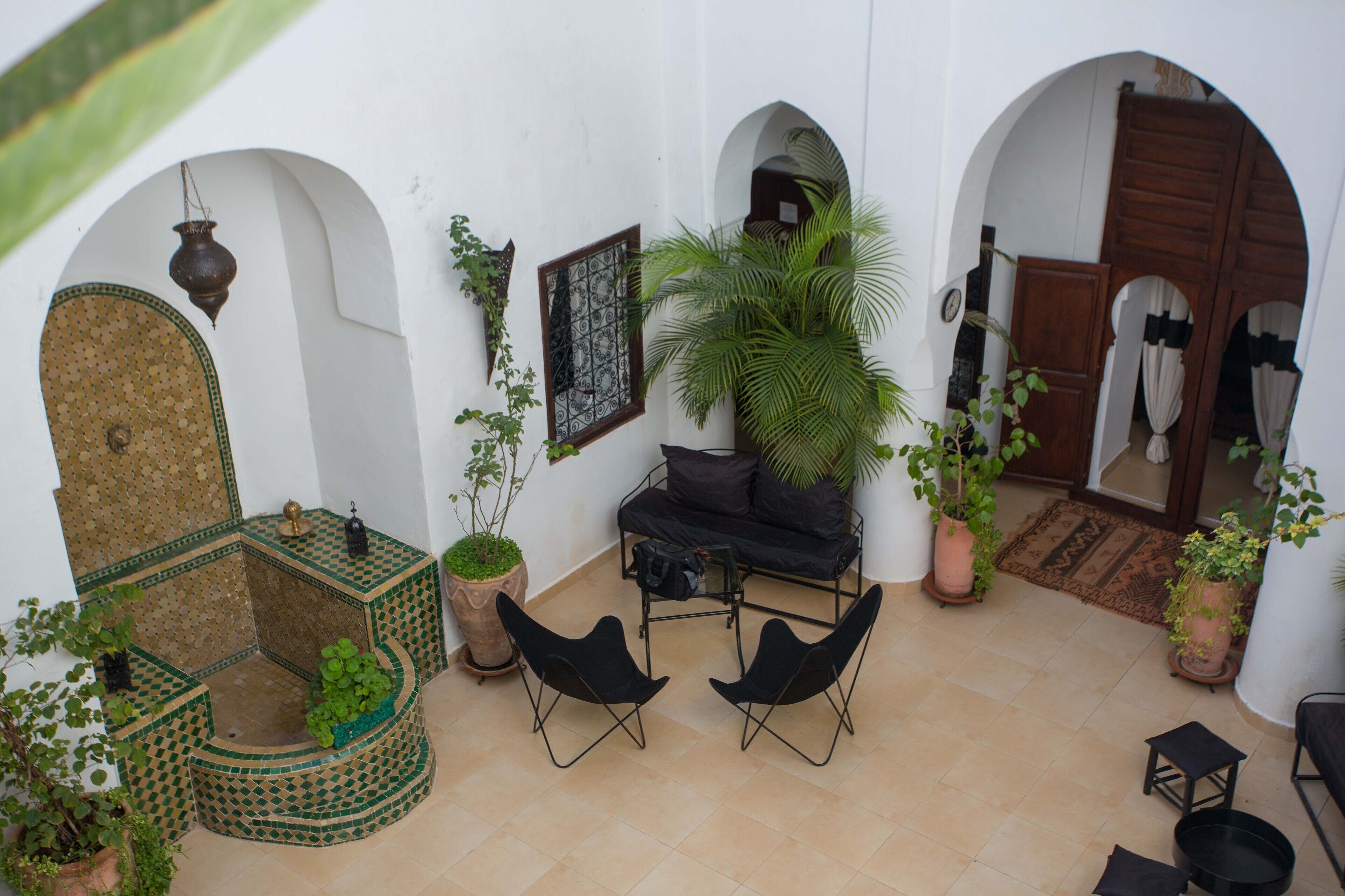A courtyard with a seating area, potted plants, and a traditional Moroccan design.