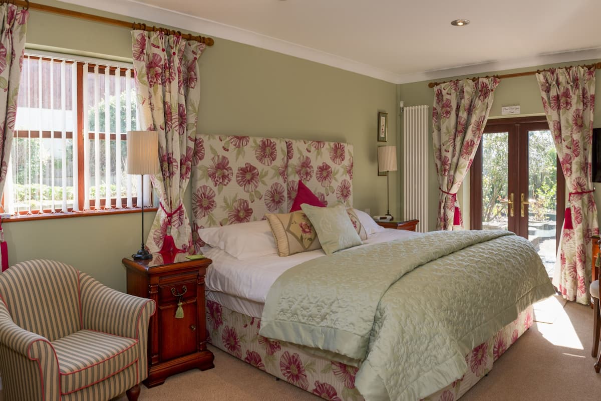A bedroom with a bed, a chair, a dresser, a television, and a window with curtains.