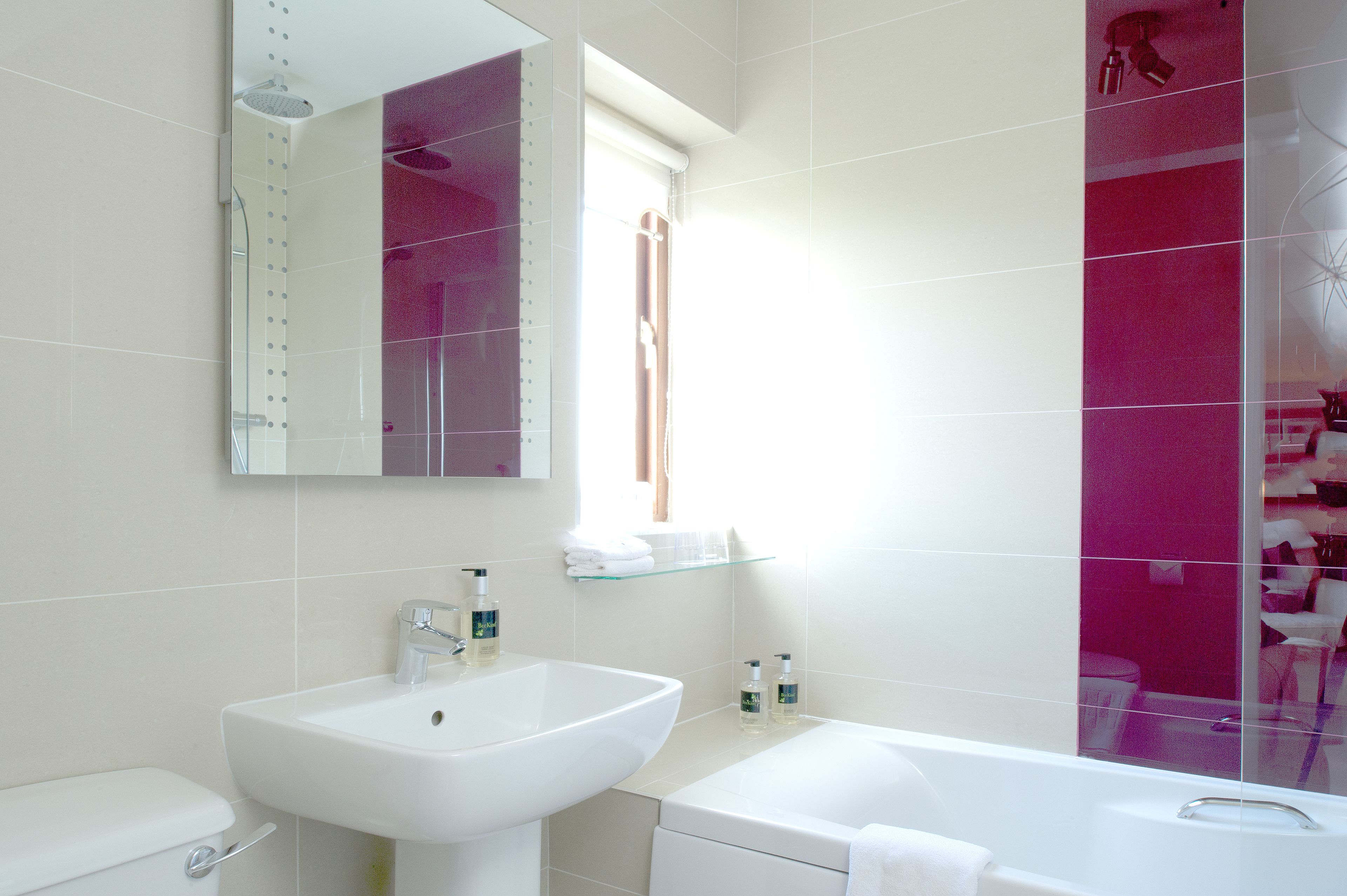 Un baño moderno con un lavamanos blanco, una bañera y un espejo grande.