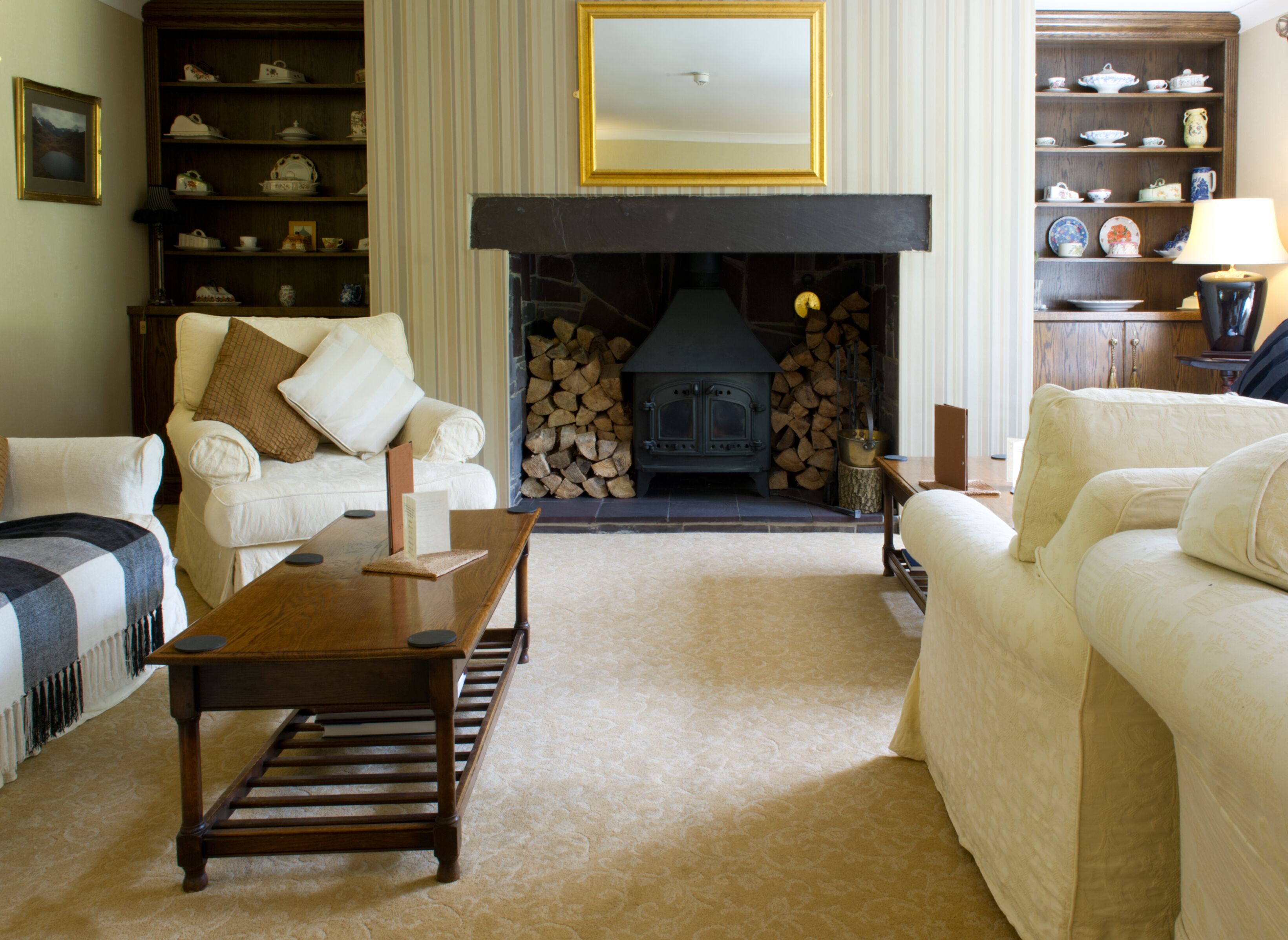 A cozy living room with a fireplace, a sofa, a coffee table, and a bookshelf.