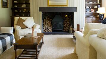 A cozy living room with a fireplace, a sofa, a coffee table, and a bookshelf.