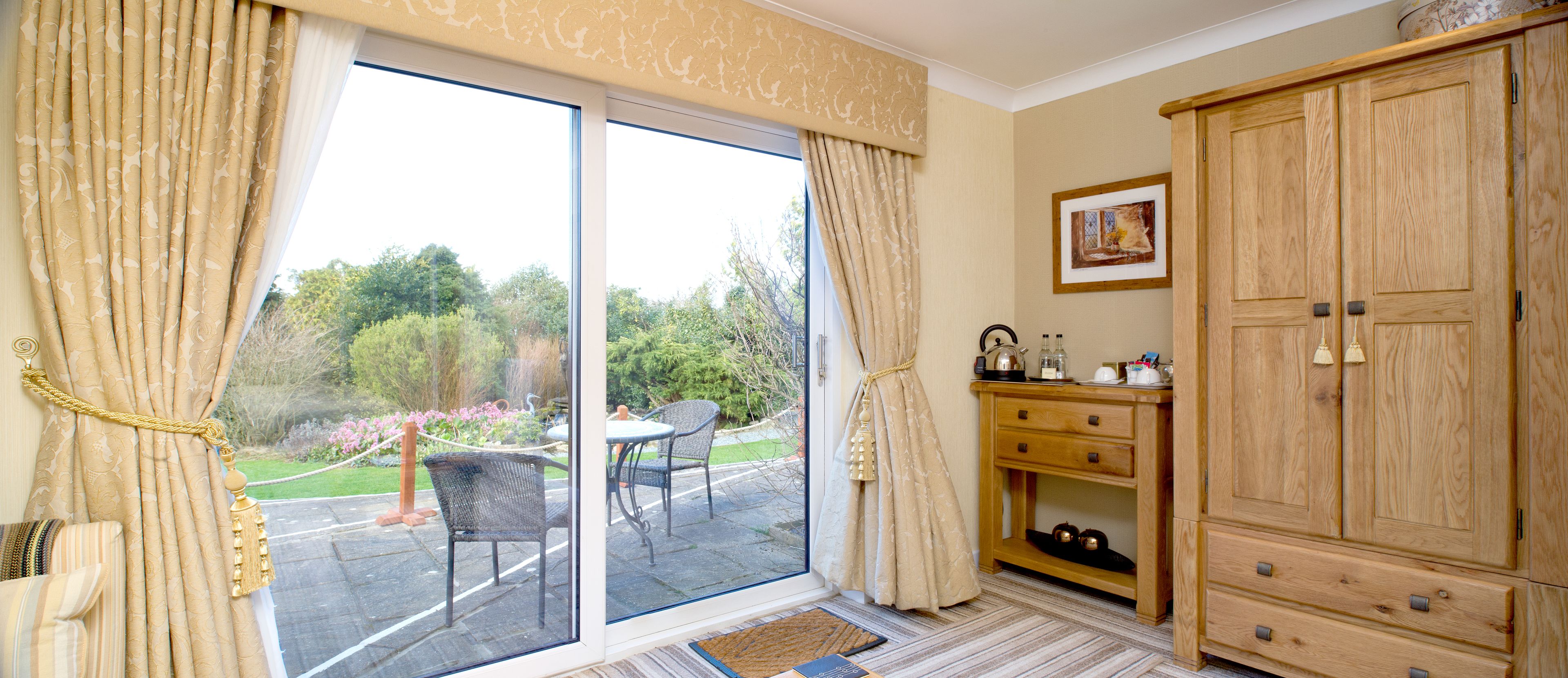 A room with a sliding glass door leading to an outdoor patio, a wooden cabinet, and a framed picture on the wall.