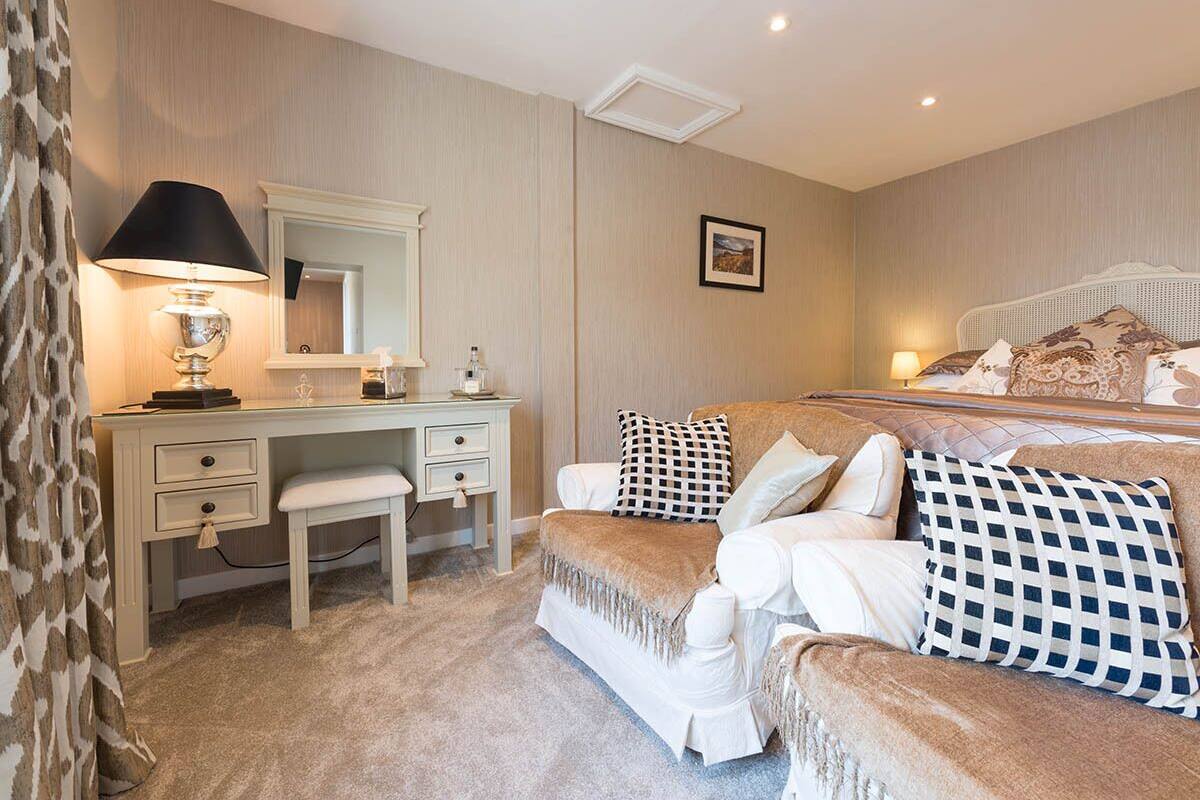 A bedroom with a bed, a desk, a chair, and a lamp.