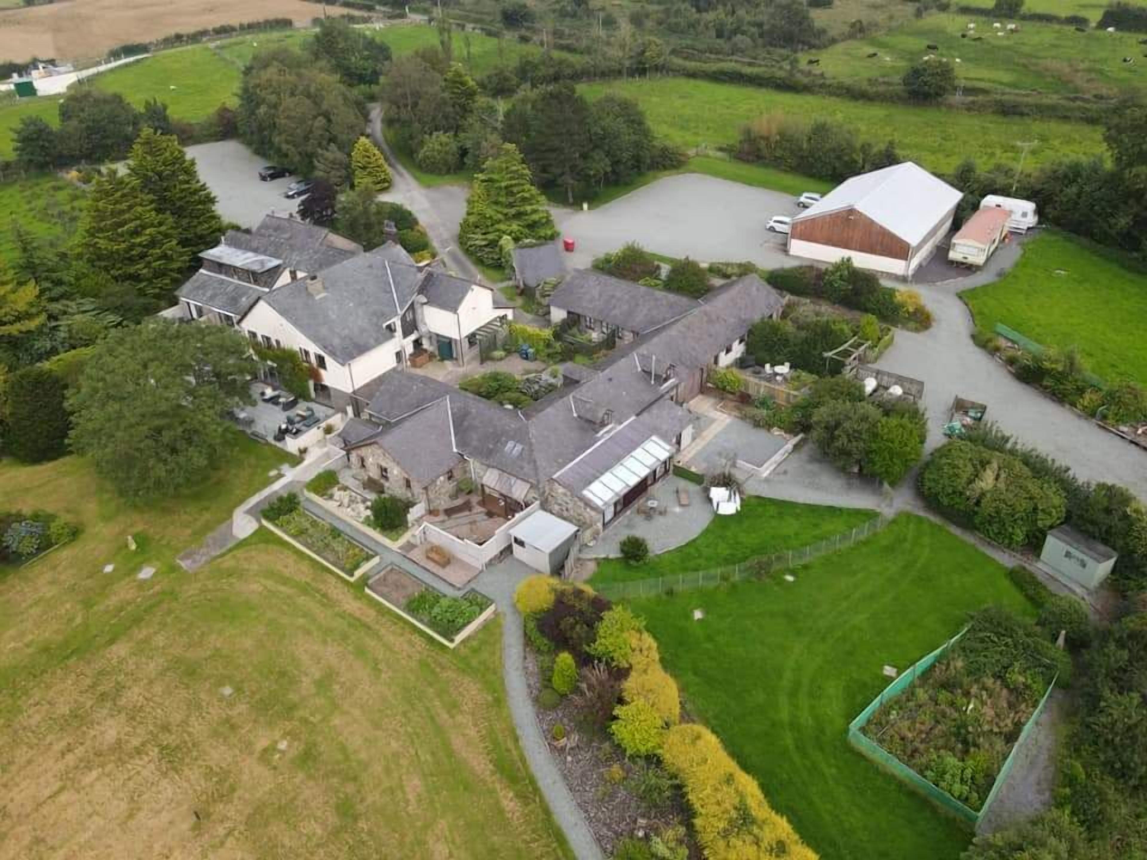 An aerial view of a residential area with multiple houses, a large barn, and surrounding greenery.