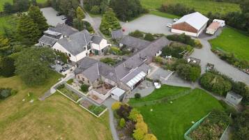 An aerial view of a residential area with multiple houses, a large barn, and surrounding greenery.