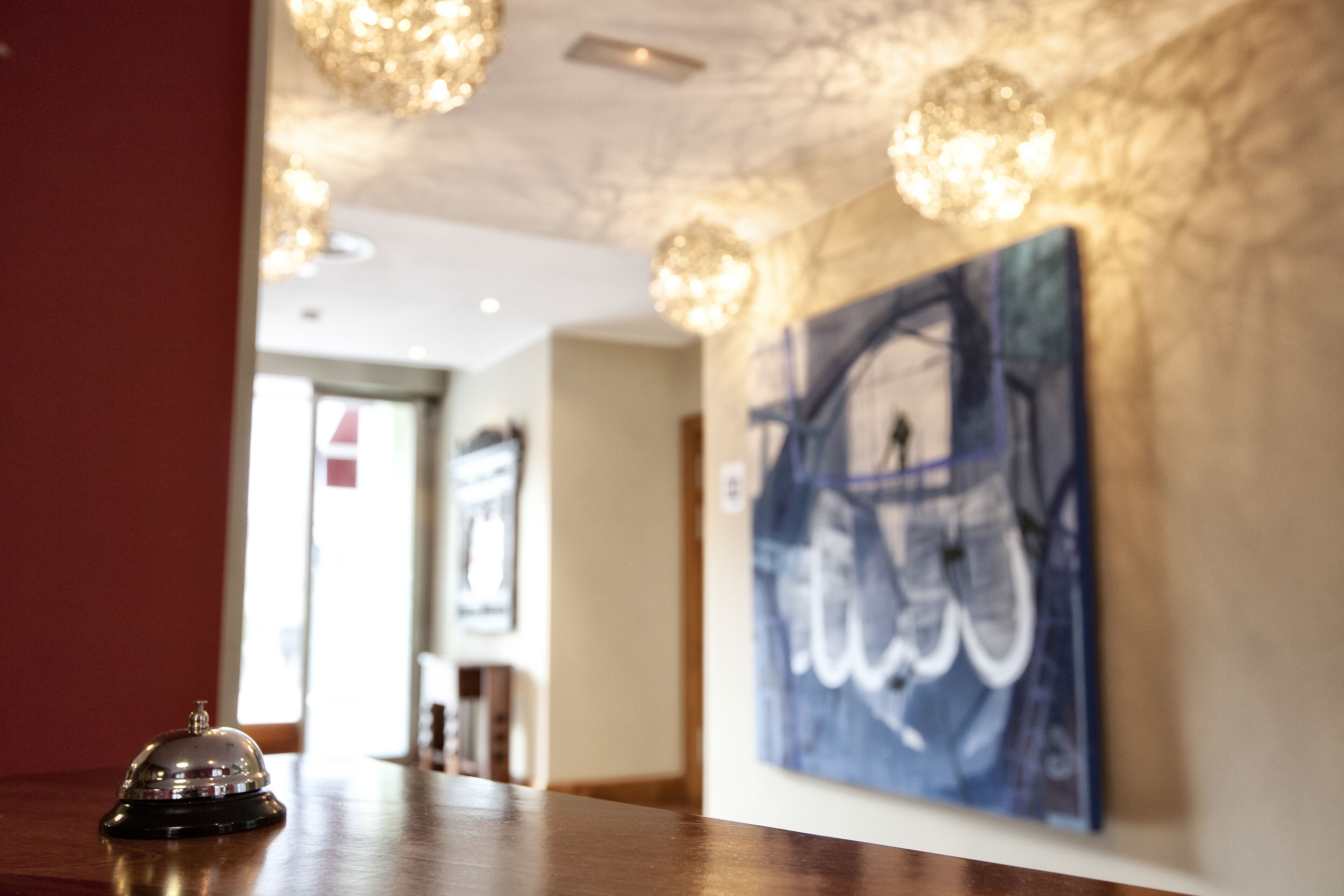 A hotel lobby with a reception area, a painting on the wall, and a chandelier.