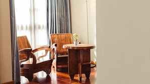 A room with a wooden chair, a round wooden table, and a floor lamp.