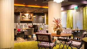 A dining area with a round wooden table, patterned chairs, and a decorative vase.