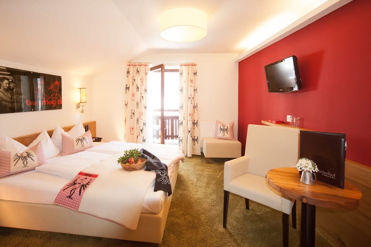 Een hotelkamer met een bed, een bureau, een stoel, een televisie en een raam met gordijnen.