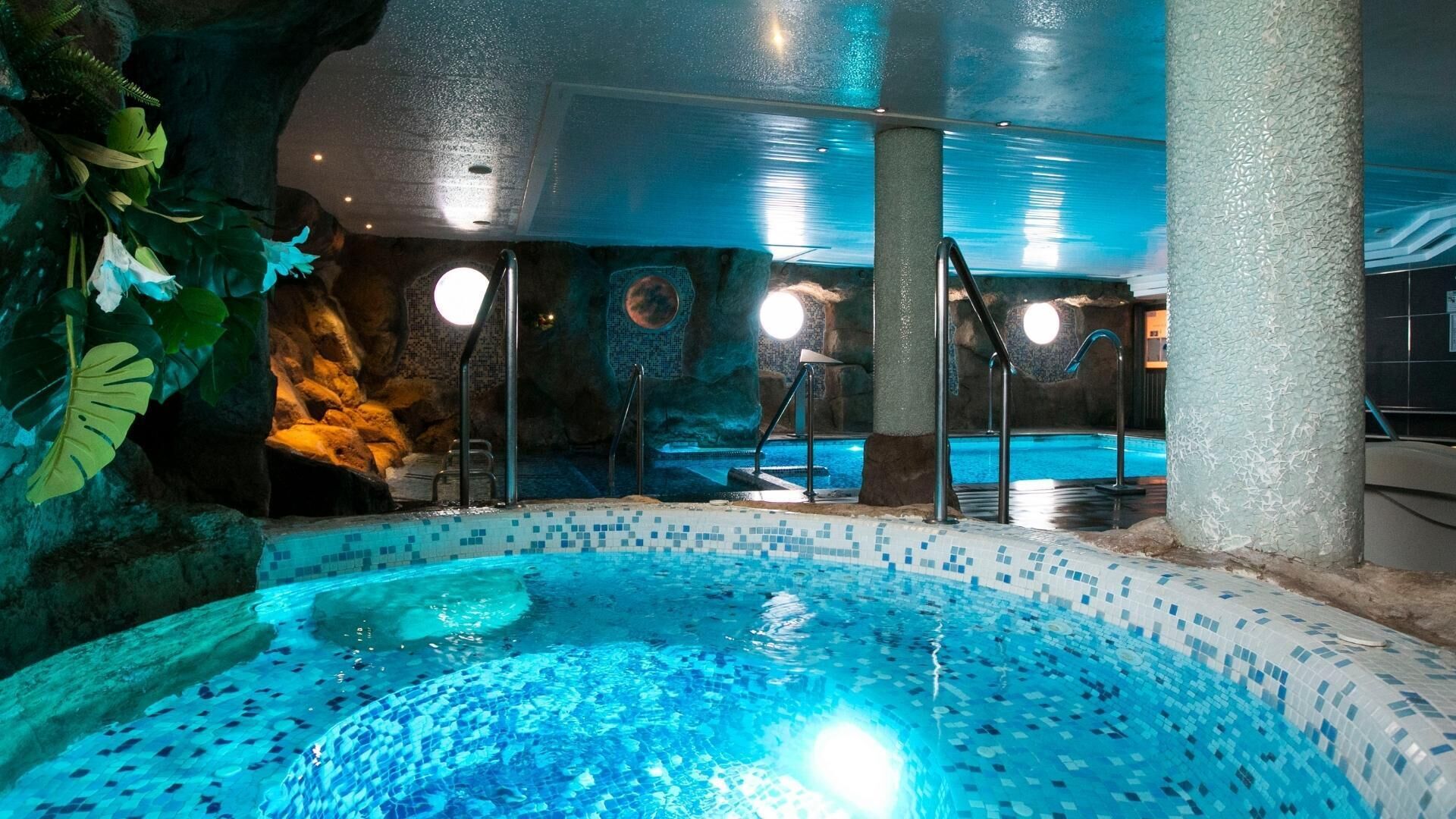 Ein Innenpool mit klarem, blauem Wasser, umgeben von Felsformationen und Pflanzenzierdekor.