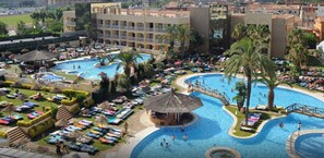 Un complexe hôtelier doté de plusieurs piscines, de chaises longues et de palmiers.