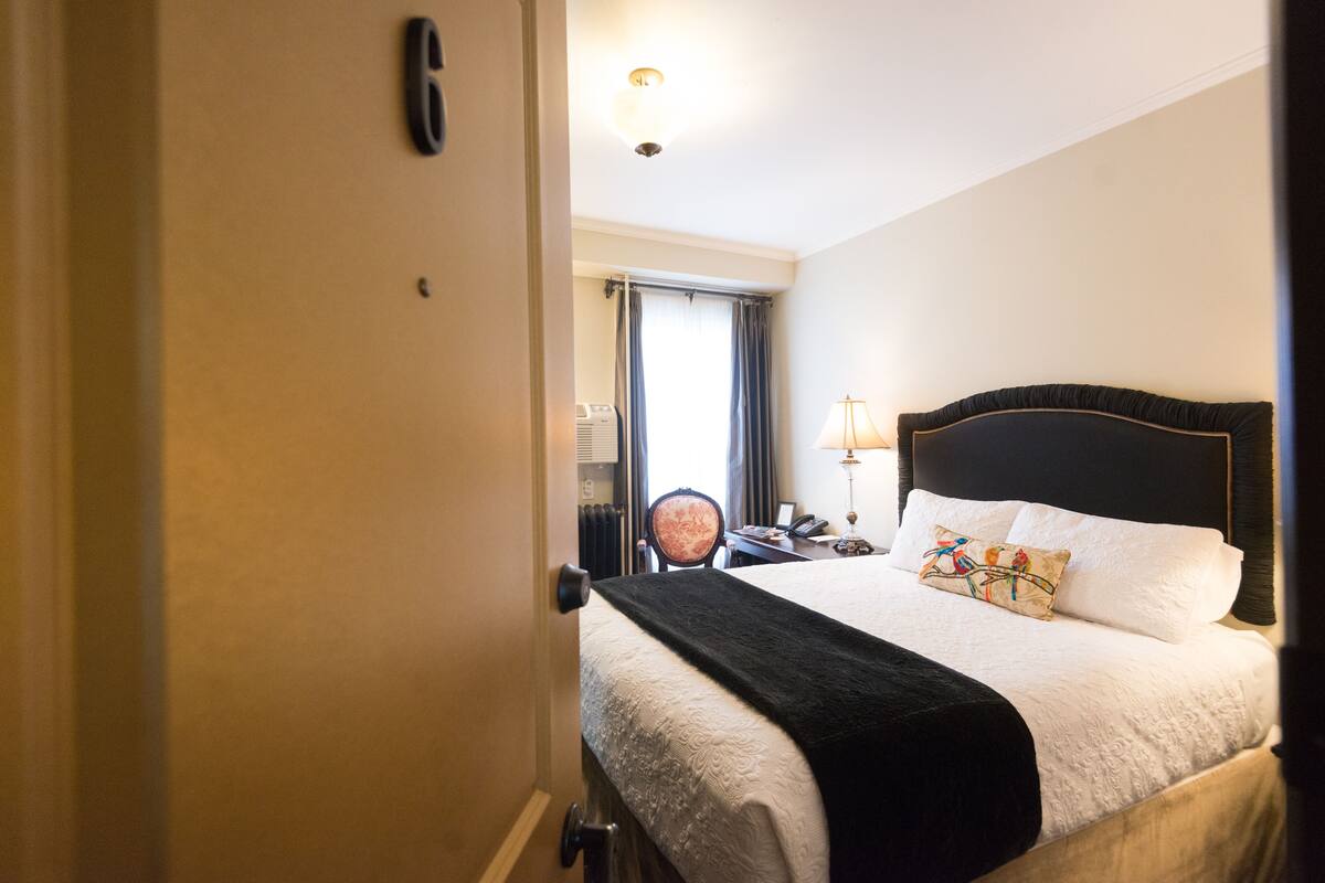 Une chambre d’hôtel avec un lit, une chaise, un bureau et une lampe.