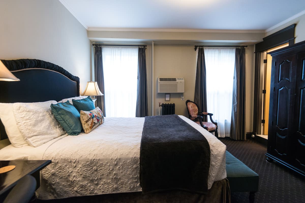 Une chambre d’hôtel avec un grand lit, une table de chevet, une chaise et une armoire.