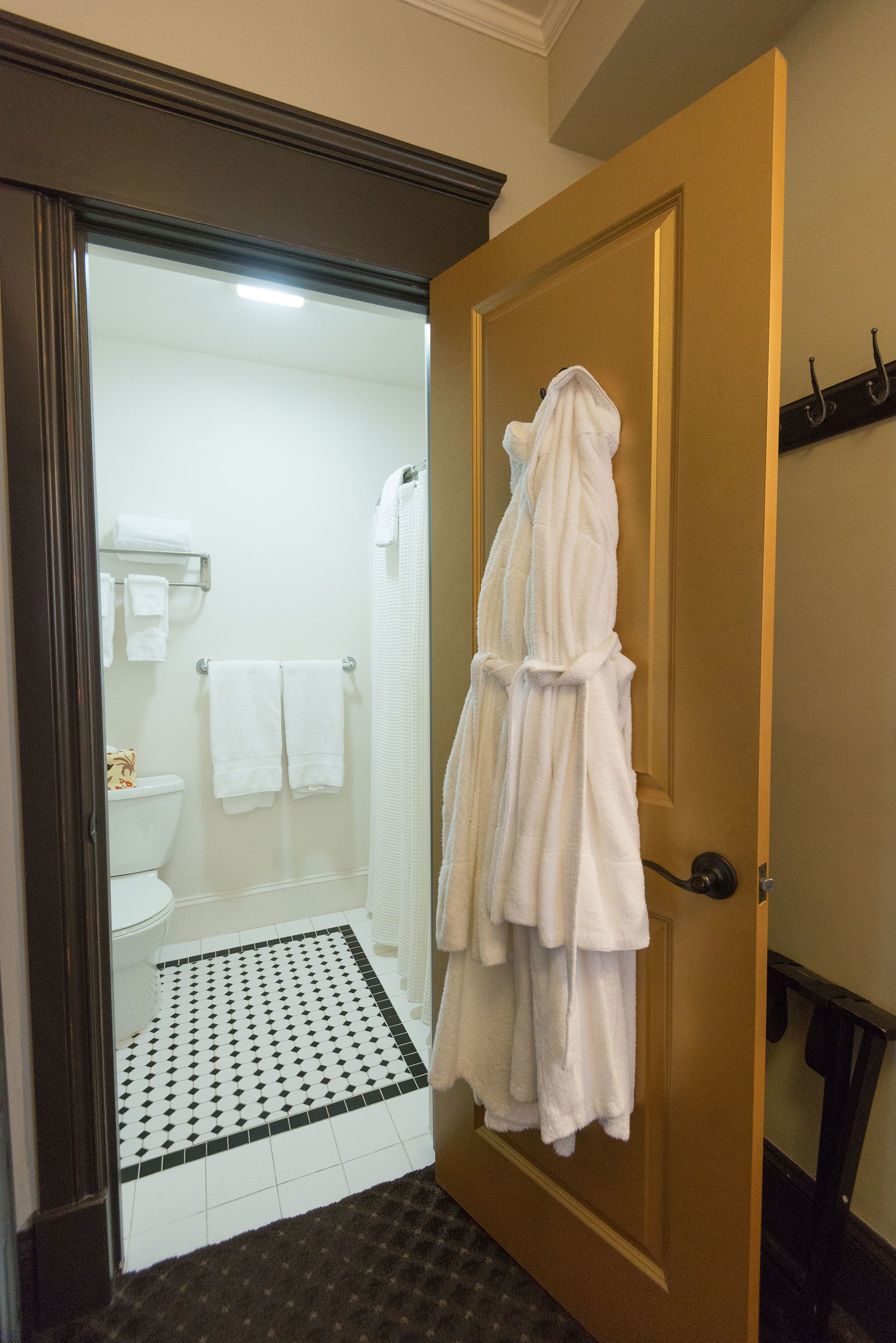 A bathroom with a toilet, a shower, and a towel rack with towels.