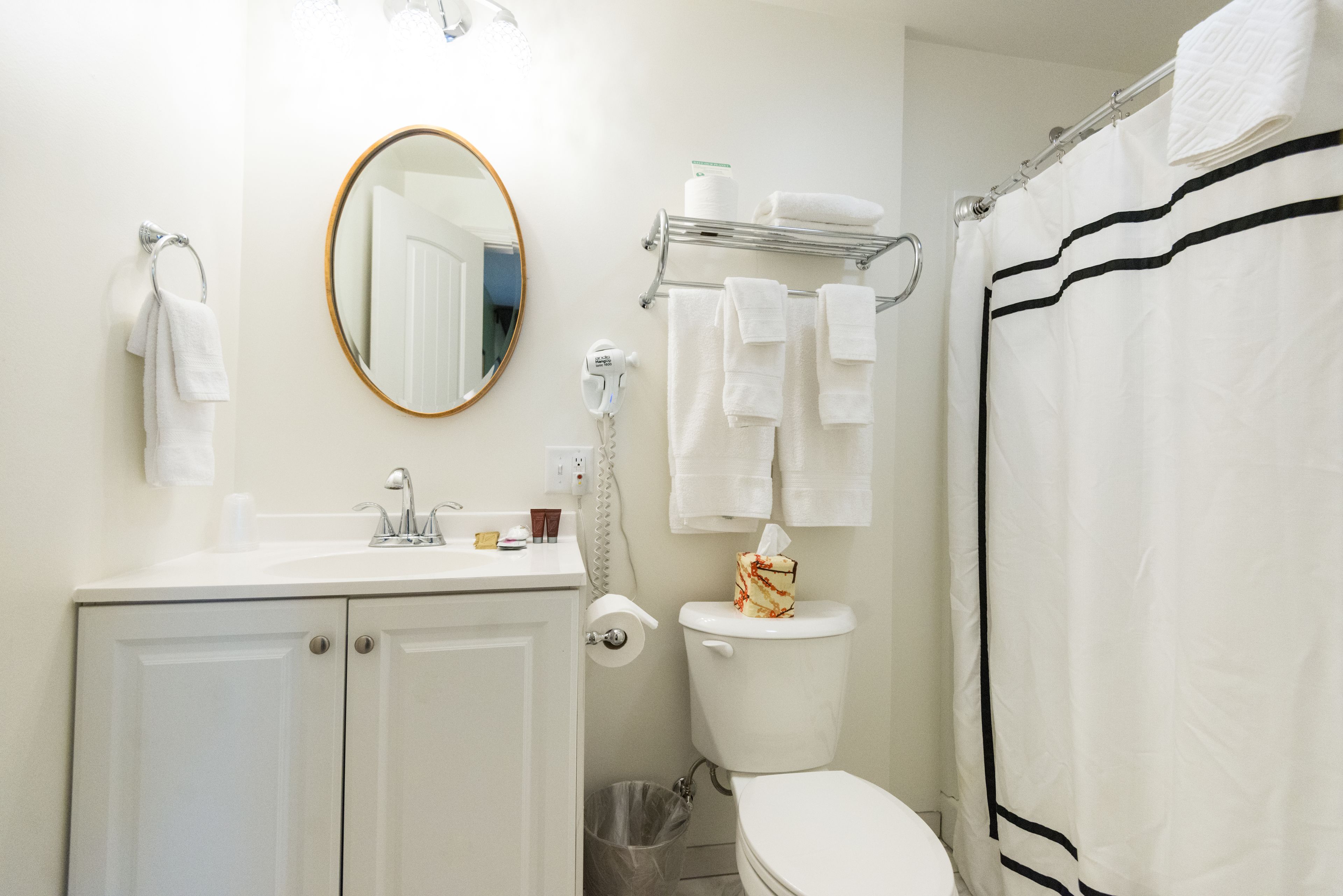 Un bagno con il water, lavandino, specchio e portasciugamani.