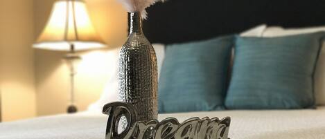 A bed with a decorative bottle and feather, and the word "Dream" on it.