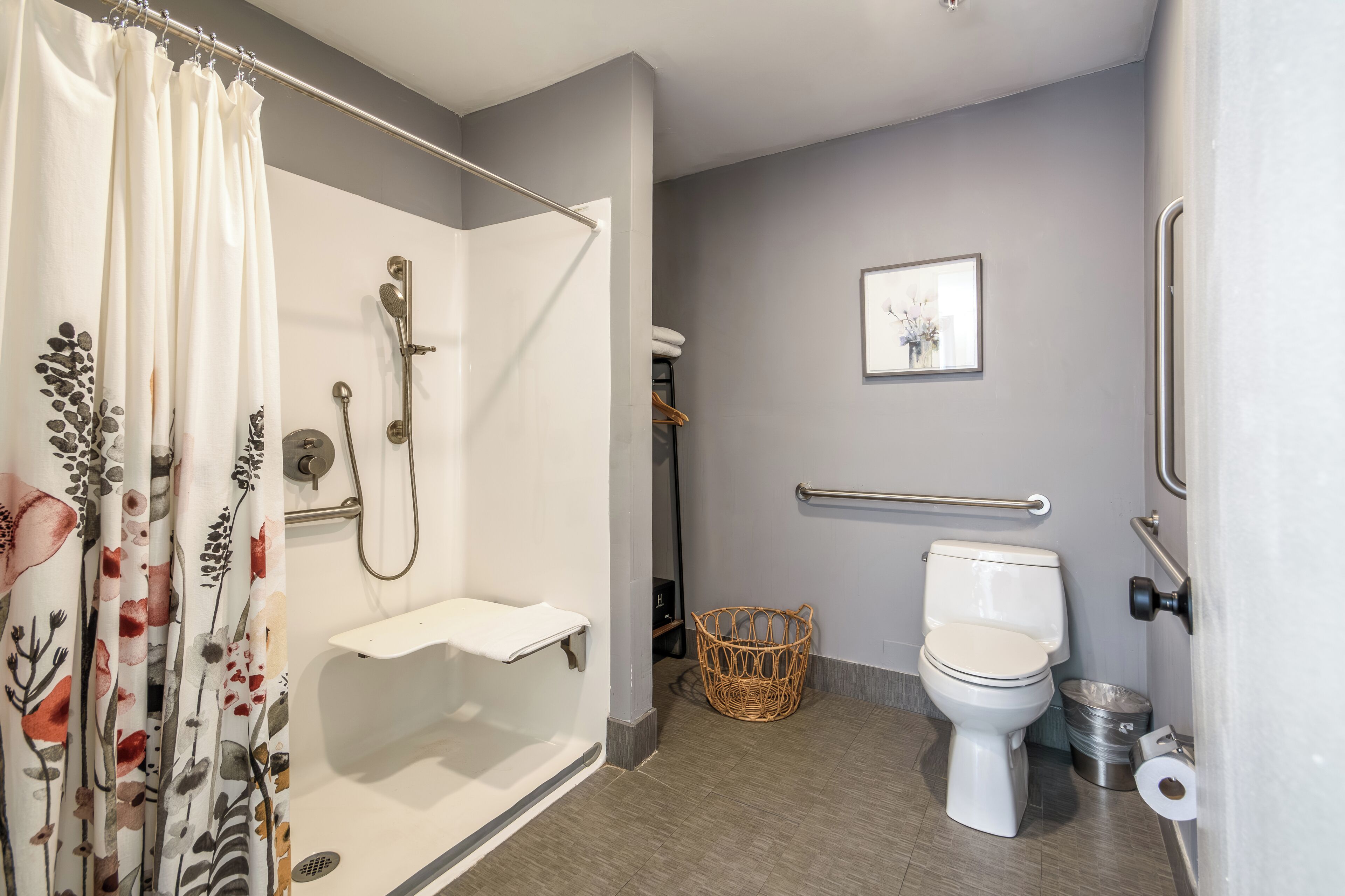 Un baño con ducha, inodoro y barra de apoyo.