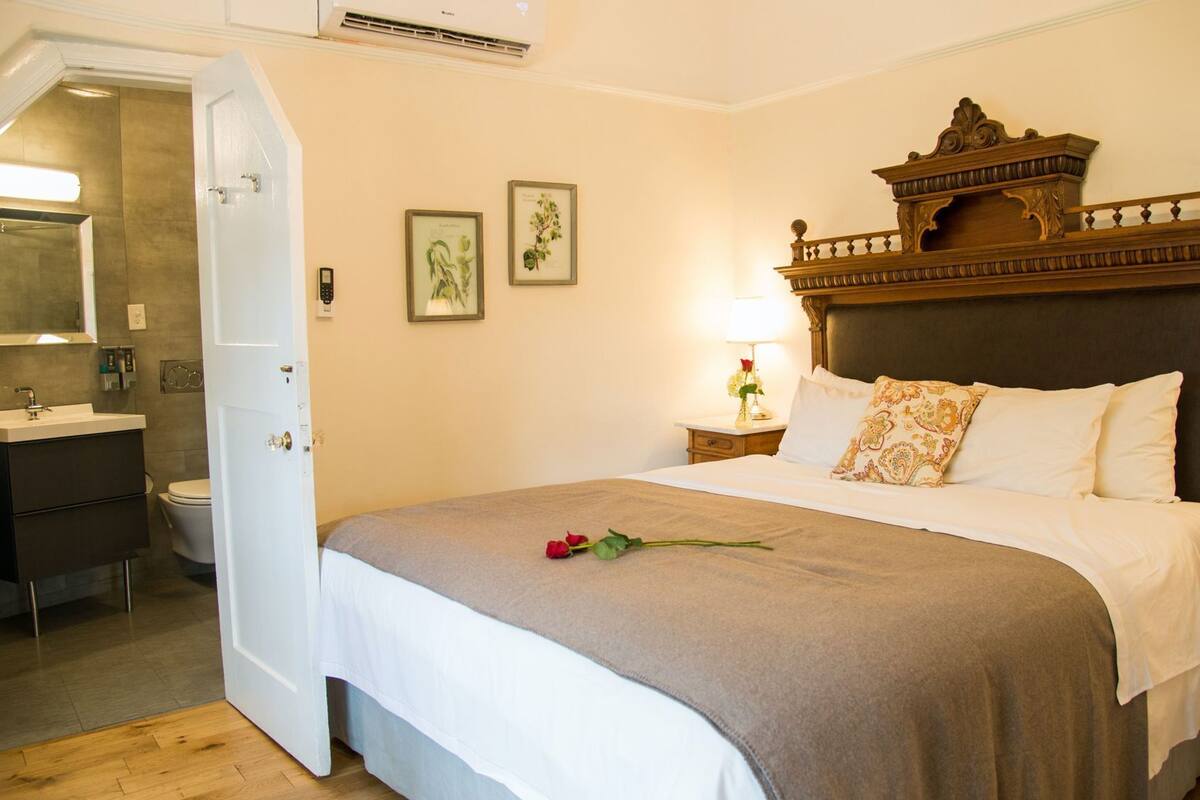 A hotel room with a bed, a bathroom, and a door leading to another room.