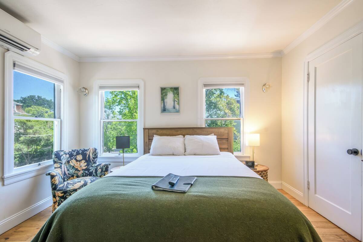A neatly arranged bedroom with a bed, a chair, and a nightstand.
