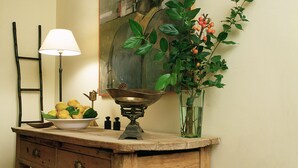 A wooden dresser with a bowl of fruit, a lamp, and a painting on the wall. - Rusticae Hotel LEstació (Bocairente)