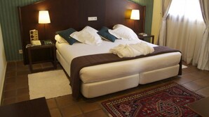 A hotel room with a large bed, two bedside lamps, a telephone, and a decorative rug. - Rusticae Hotel LEstació (Bocairente)