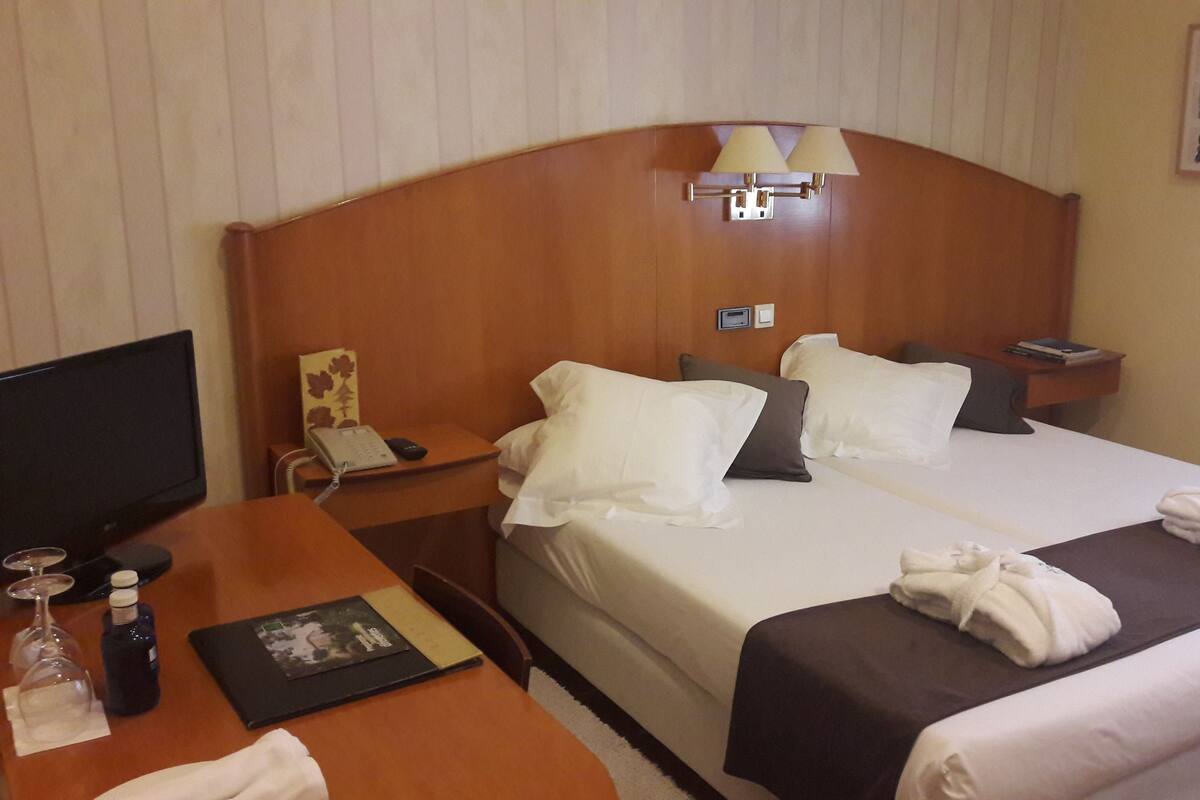 Une chambre d’hôtel comprenant un lit, des tables de chevet, un bureau, une télévision et une lampe.