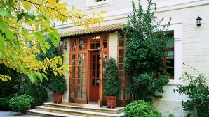 A building with a traditional wooden front door, a set of steps leading to the entrance, and potted plants around the entrance area. - Rusticae Hotel LEstació (Bocairente)
