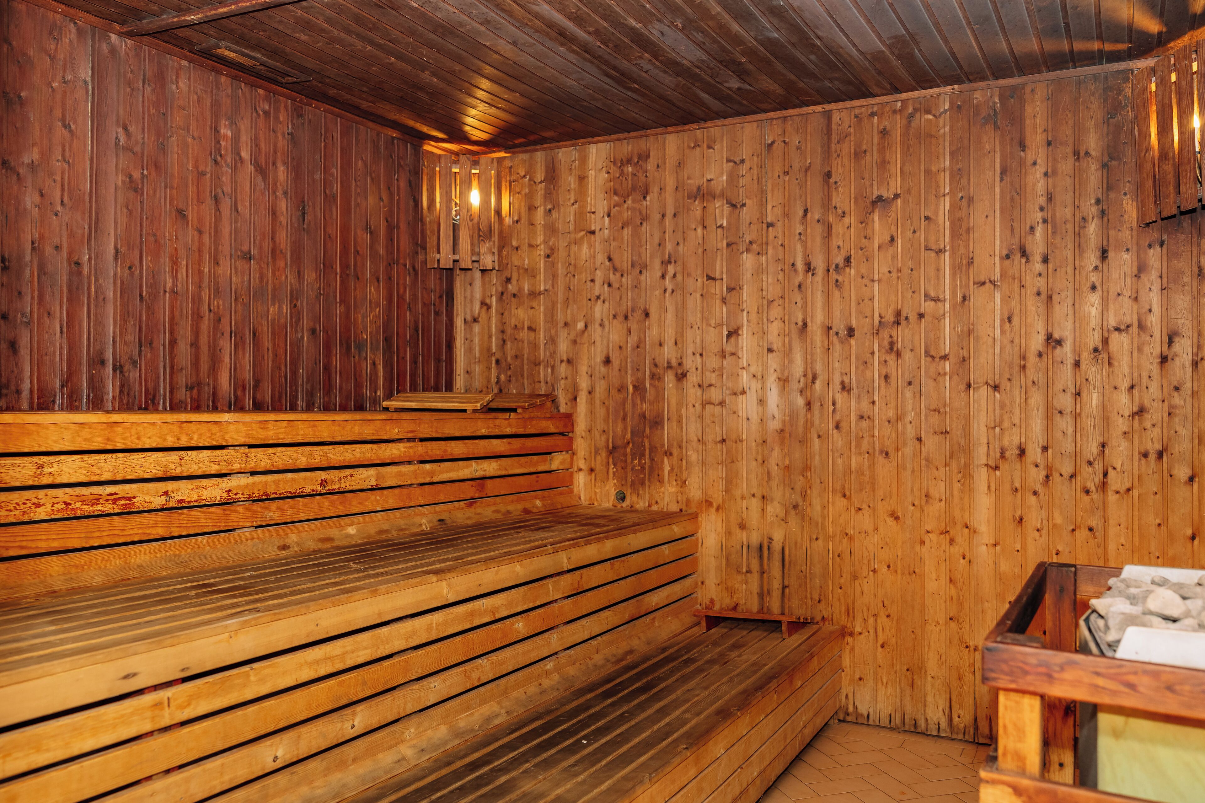 Eine Holzsauna mit Bänken und einer Steinsitzbank.