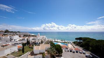 Zona residencial costera con edificios blancos, piscina y vista al mar.