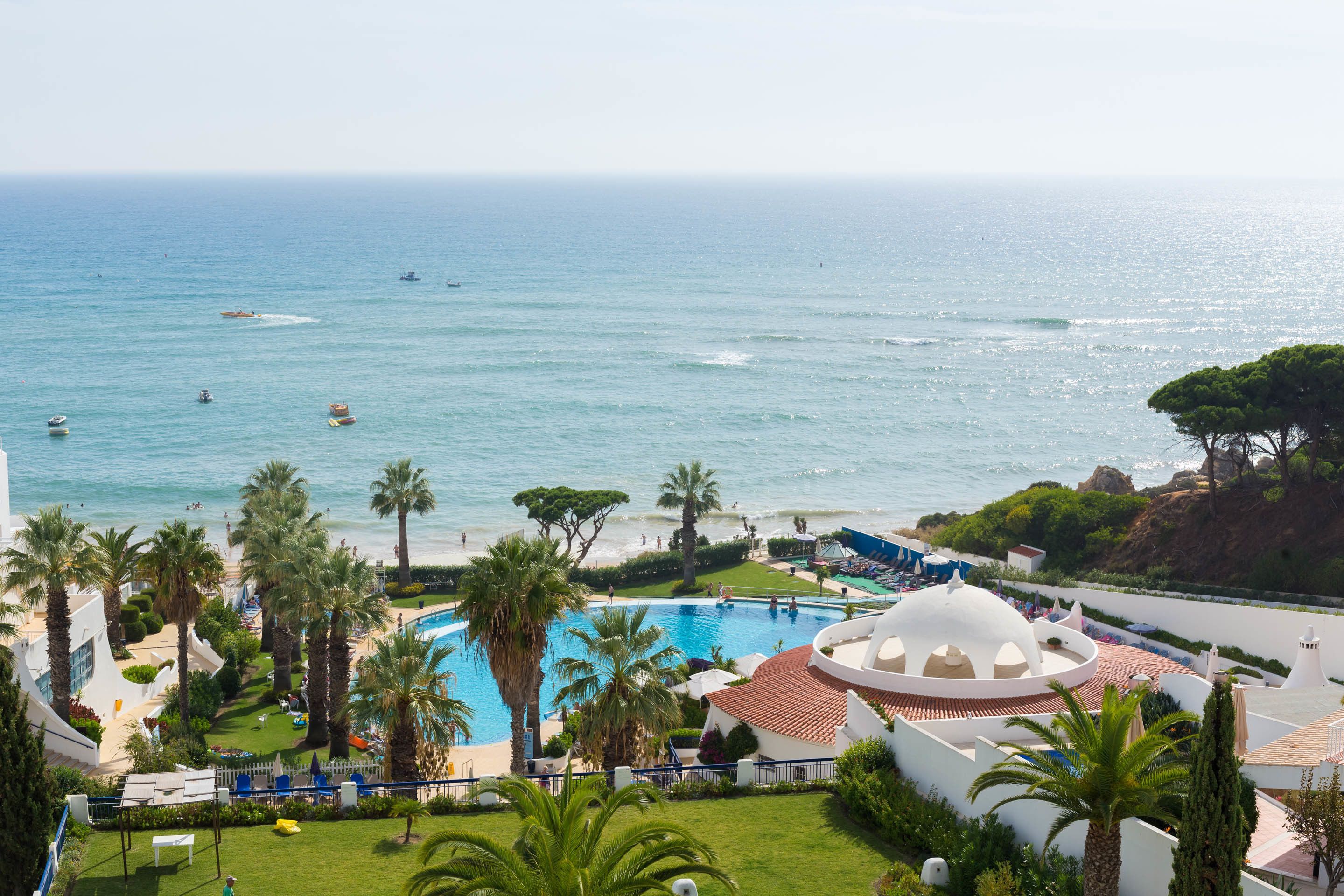 Een resort met een zwembad, palmbomen en uitzicht op de oceaan.
