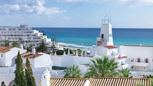 A coastal town with white buildings, a prominent white church with a blue dome, and a view of the sea. - Grand Muthu Oura View Beach Club (Albufeira)